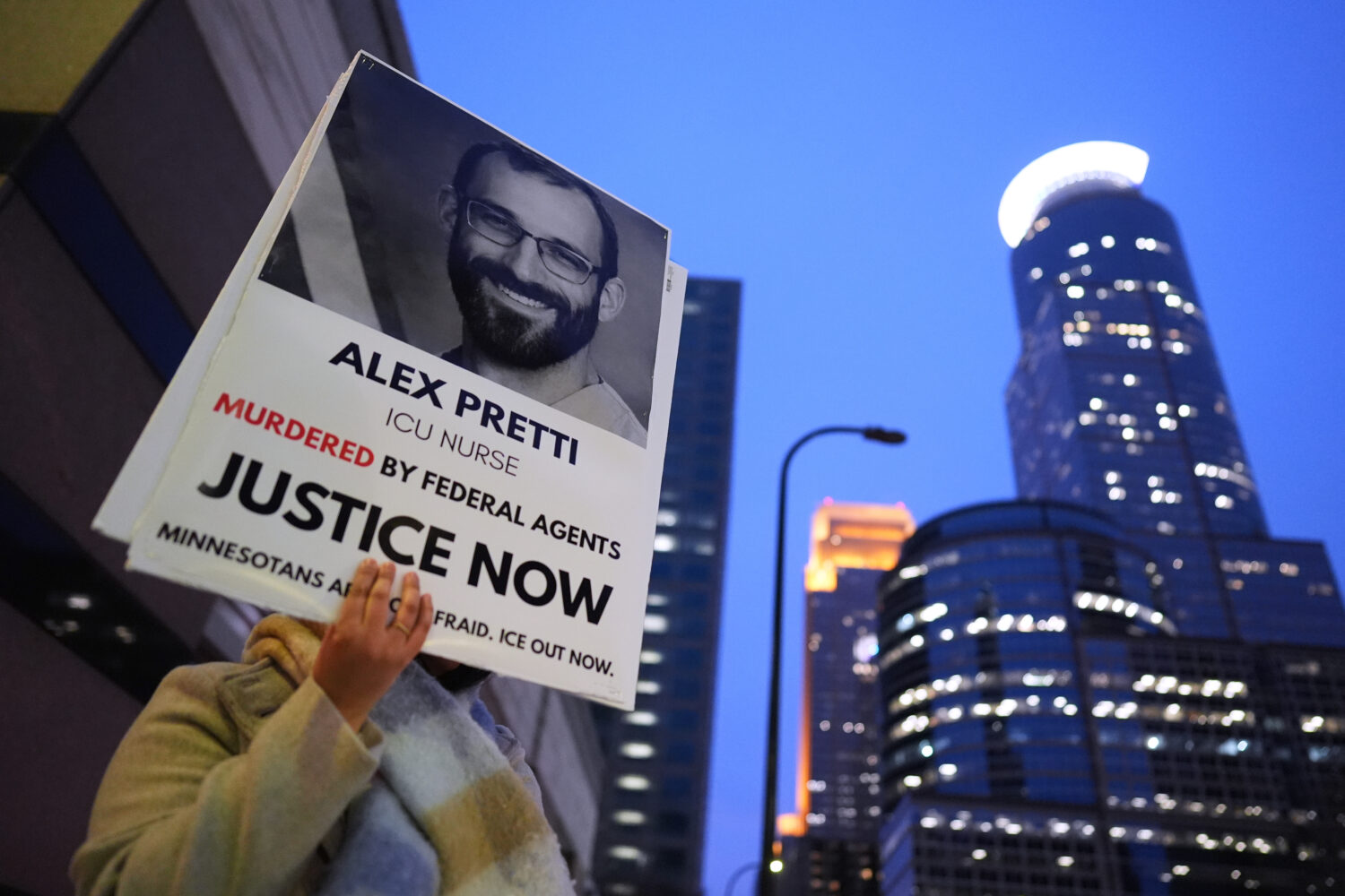 A person holds a sign of Alex Pretti during a protest outside the office of Sen. Amy Klobuchar, D-M...