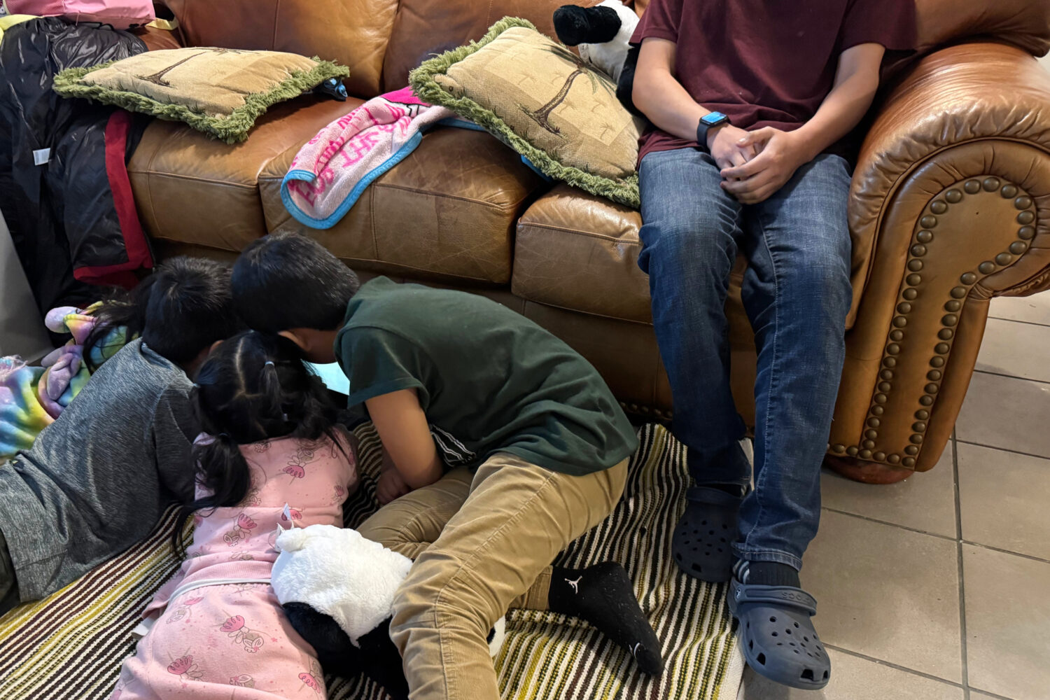 A boy sits on the couch of a Minneapolis safe house Friday, Jan. 16, 2026, as his younger siblings ...