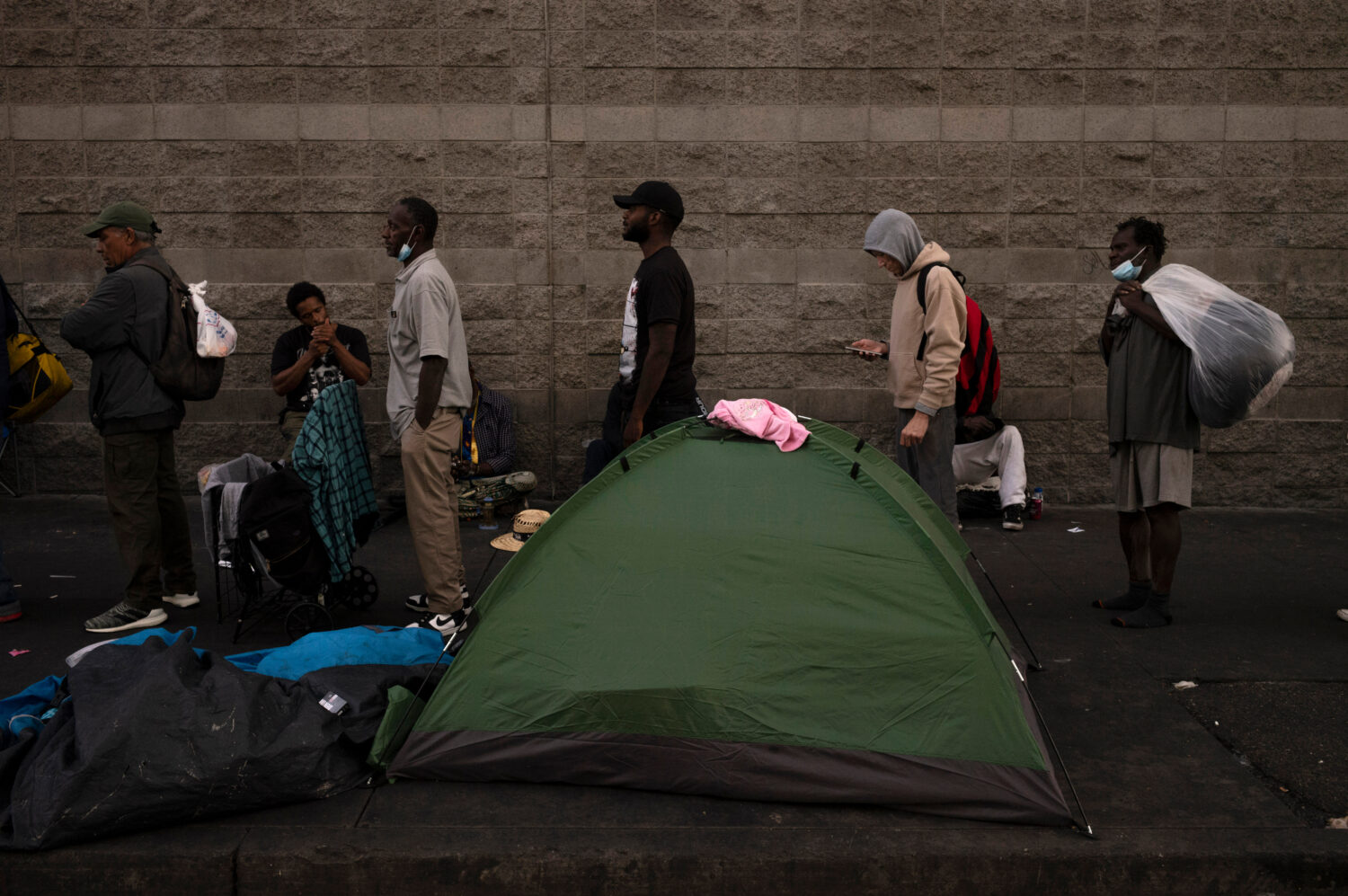 FILE - Homeless people wait in line for dinner outside the Midnight Mission in the Skid Row area of...