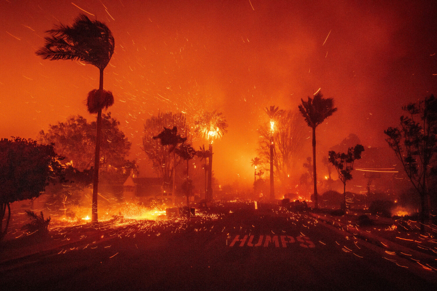 FILE - Embers blow down a street as the Palisades Fire ravages a neighborhood amid high winds in th...