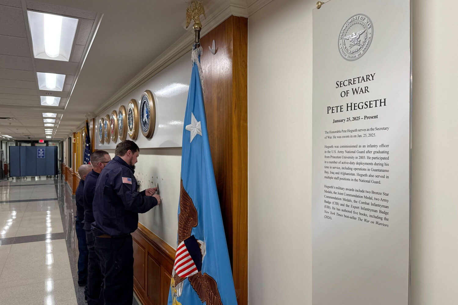 FILE - Workers remove sign lettering at the Pentagon after President Donald Trump signed an executi...