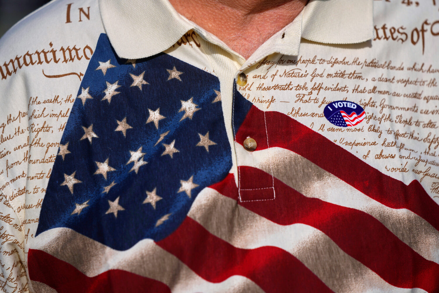 FILE - A man wears an "I voted" sticker on his shirt, printed with the American flag and the U.S. c...