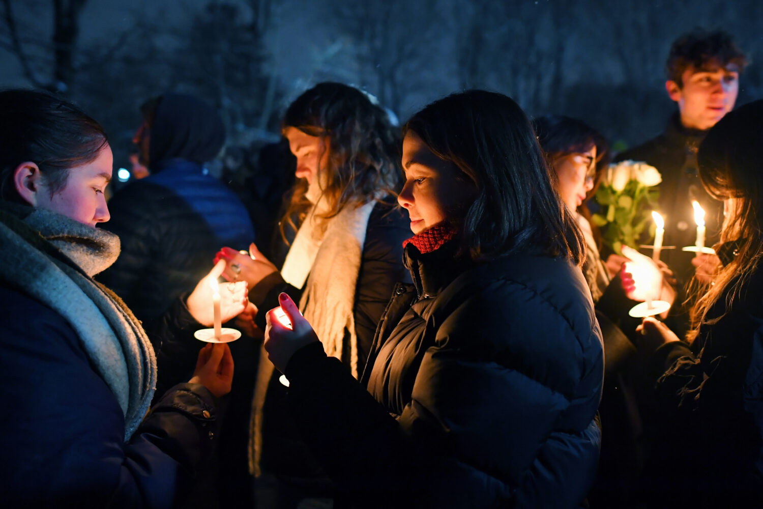 FILE - People hold candles during a vigil, Dec. 14, 2025, in Providence, R.I., for the victims of S...