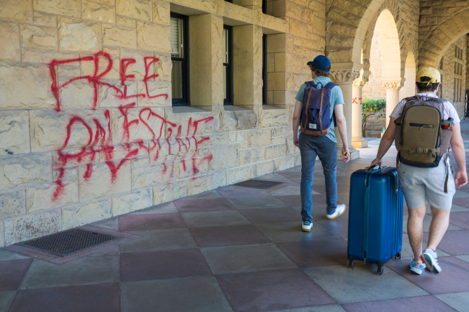 FILE - Students walk by graffiti near university president Richard Saller's office at Stanford Univ...