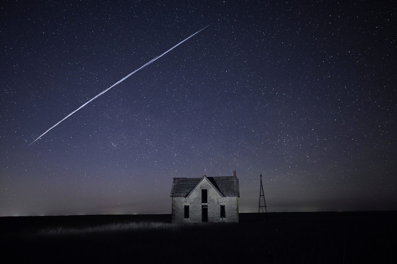 FILE - In this long exposure photo, a string of SpaceX StarLink satellites passes over an old stone...