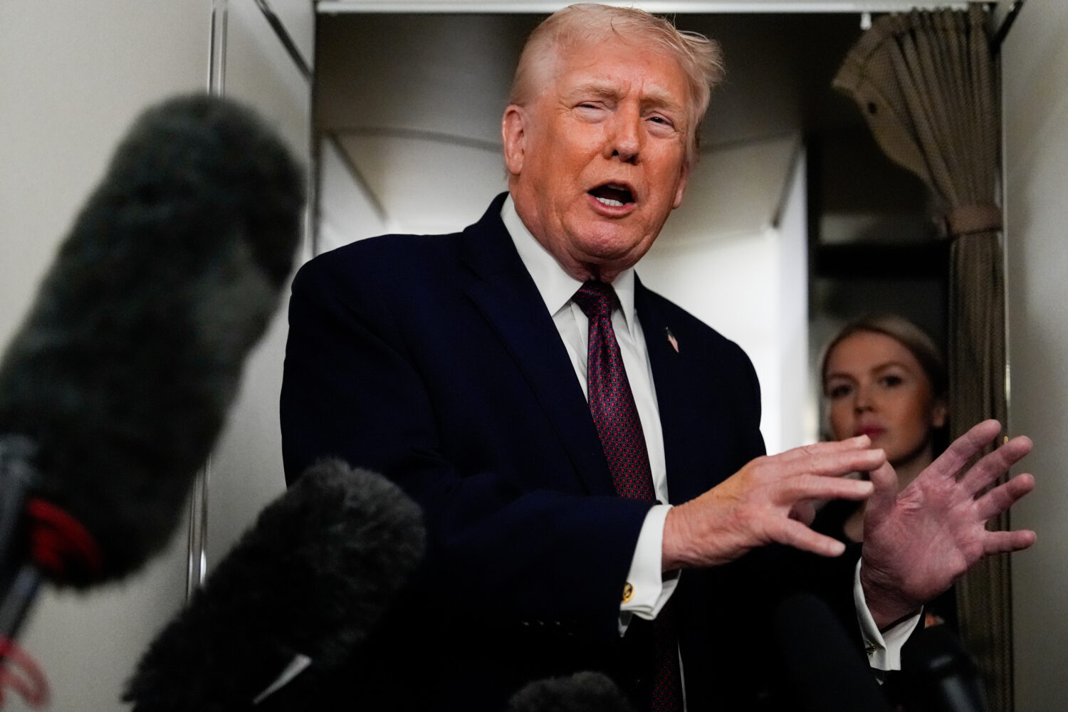 President Donald Trump speaks to reporters while in flight on Air Force One to Joint Base Andrews, ...