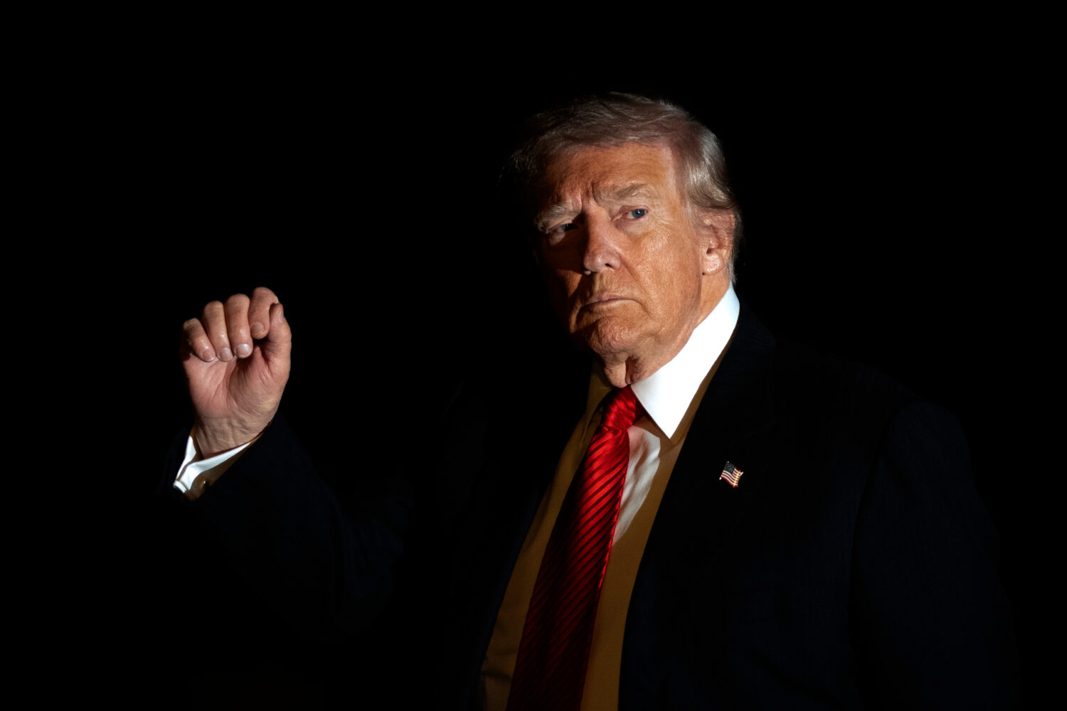 FILE - President Donald Trump is illuminated by a camera flash as he gestures while walking across ...