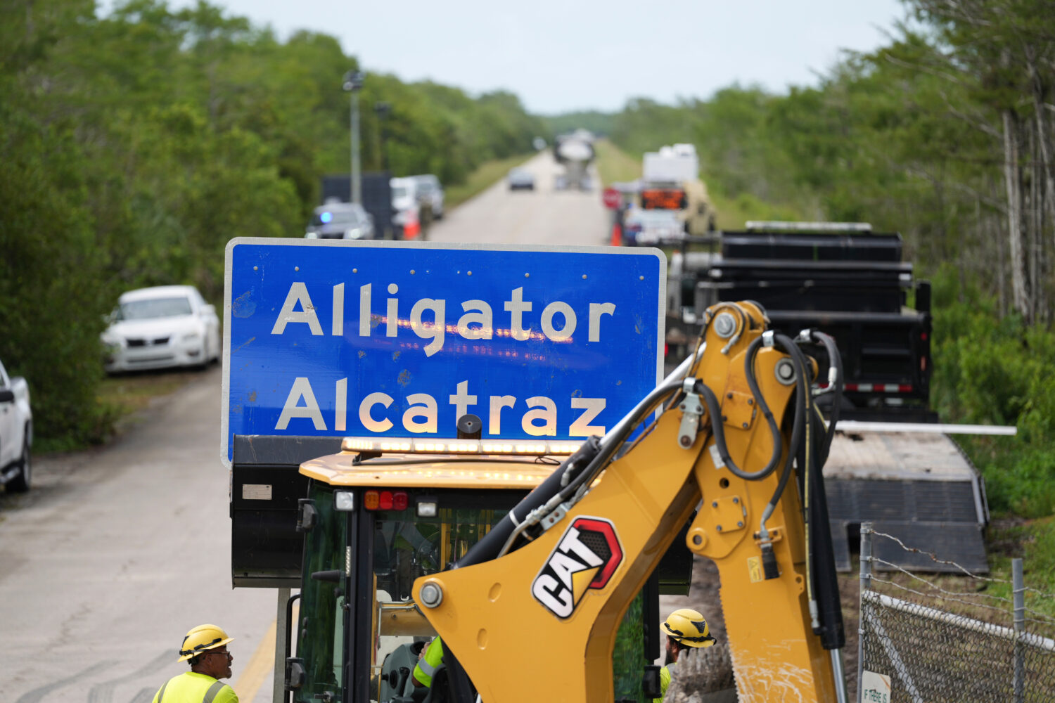 FILE - A loader holds a sign reading "Alligator Alcatraz" in its bucket as workers install it at th...