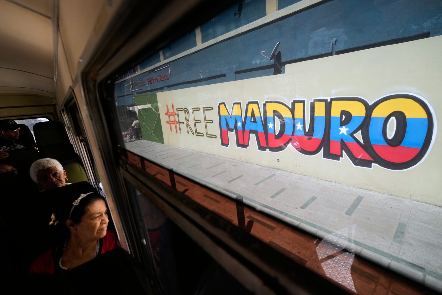 Commuters ride a bus past a mural calling for the release of former Venezuelan President Nicolas Ma...