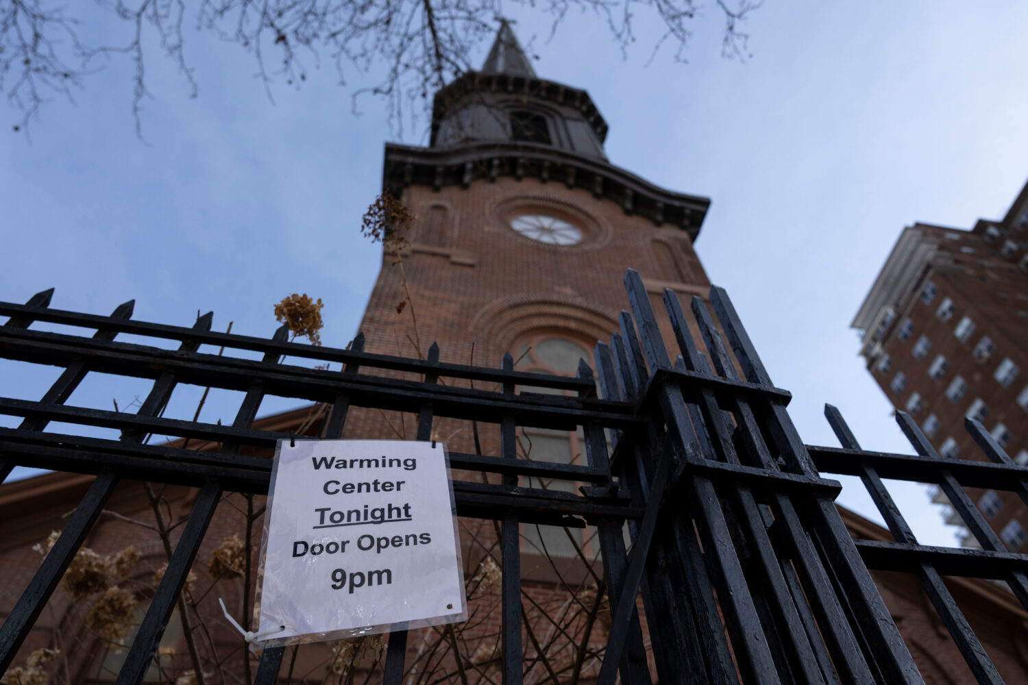 A sign showing the opening hour for warming center is displayed outside Holy Apostle Soup Kitchen, ...