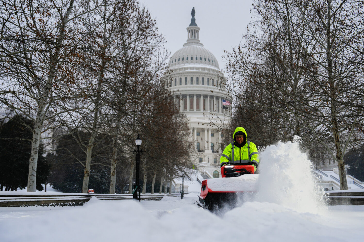 Architect of the Capitol workers clear snow outside the U.S. Capitol, Sunday, Jan. 25, 2026, in Was...