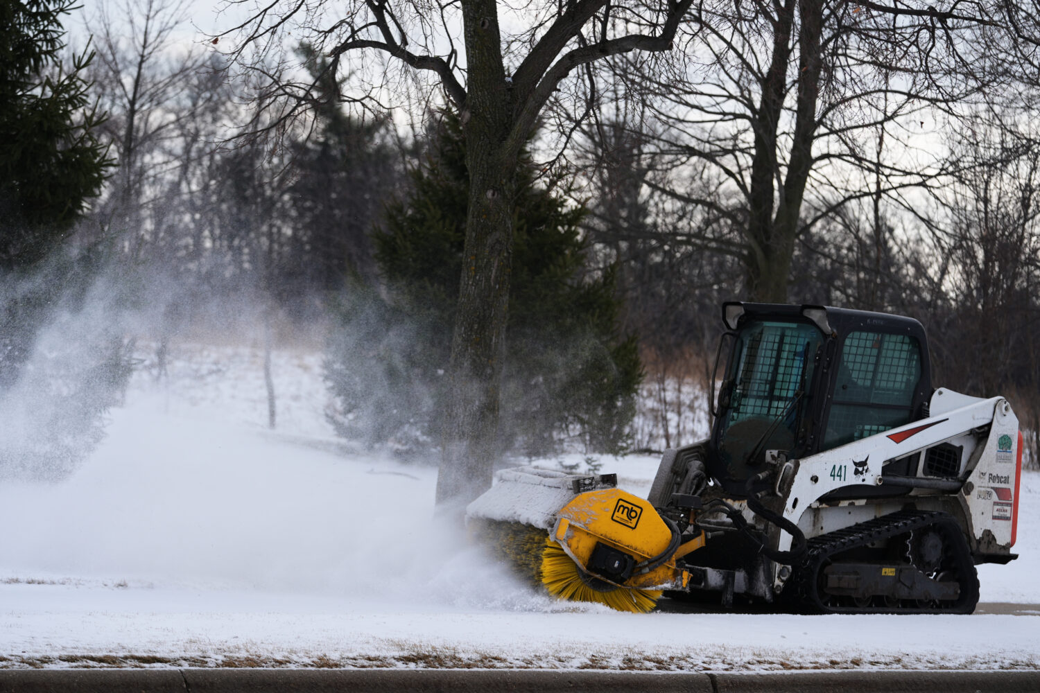 A plow clears snow from a snow-covered sidewalk during a cold day in Lake Forest, Ill., Wednesday, ...