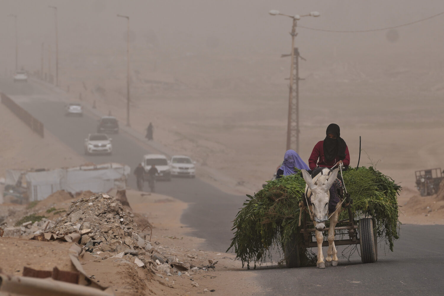 Palestinian women ride a donkey cart along the coastal road in Wadi Gaza during a dust storm in the...