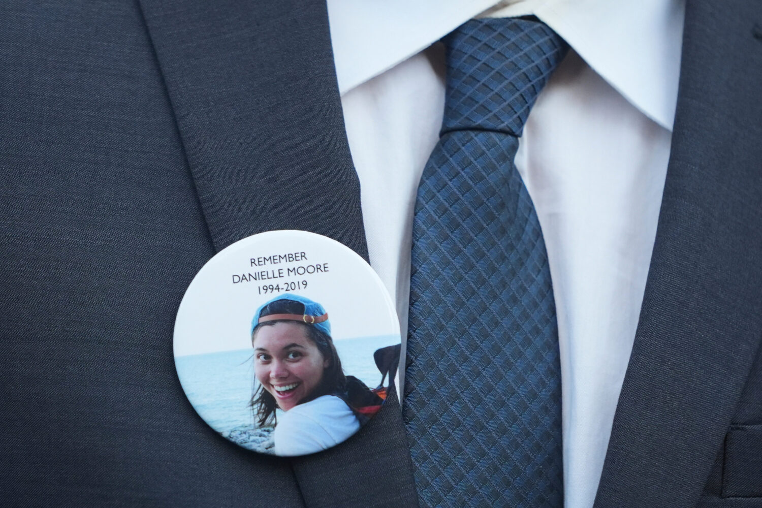 FILE - A family member wears a photo of Boeing crash victim Danielle Moore before a hearing at fede...