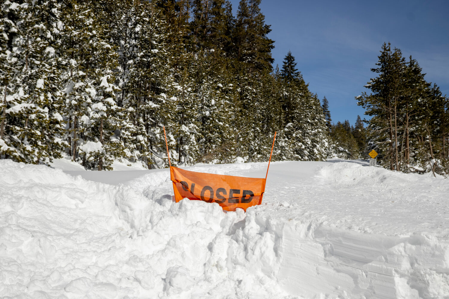 A closed sign is partially buried at the entrance to the Castle Peak trailhead in Soda Springs, Cal...