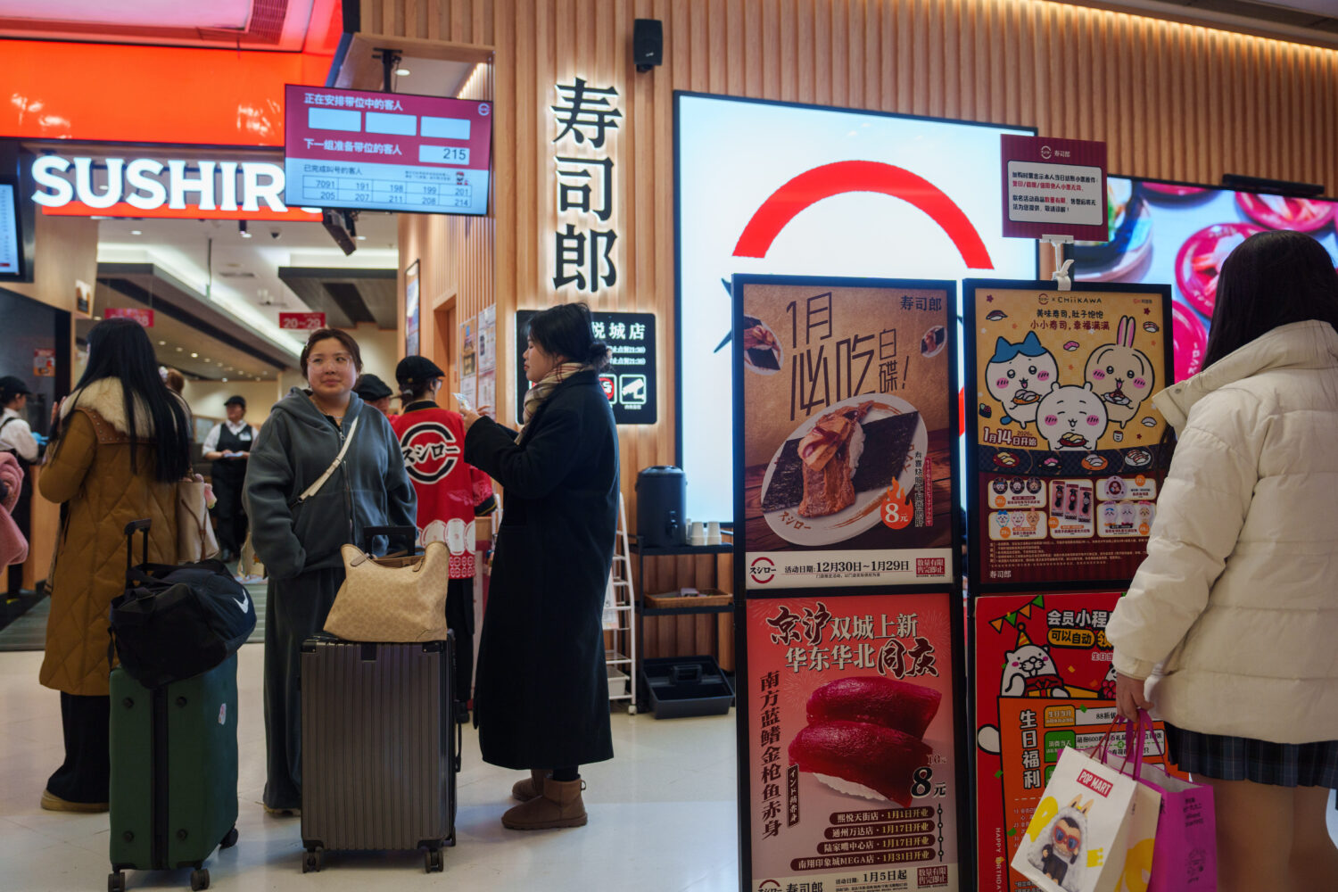 Customers wait outside a store for Sushiro, a Japan-based conveyor-belt sushi chain, in Beijing, We...
