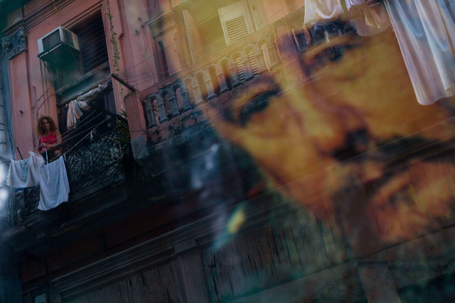 FILE - A Cuban woman hanging laundry on her balcony is seen reflected in a glass window decorated w...