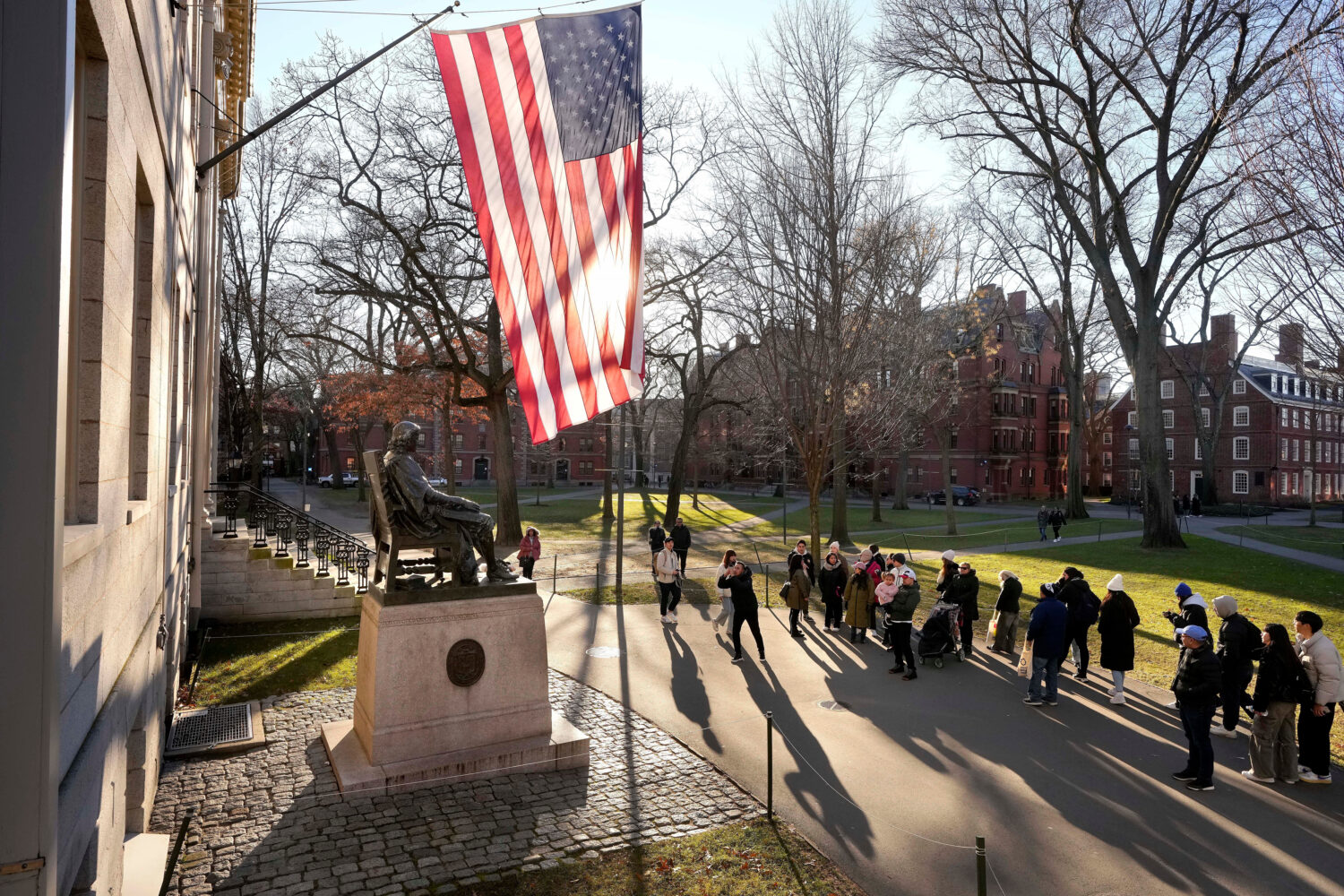 FILE - People take photos near a John Harvard statue, left, on the Harvard University campus, Jan. ...