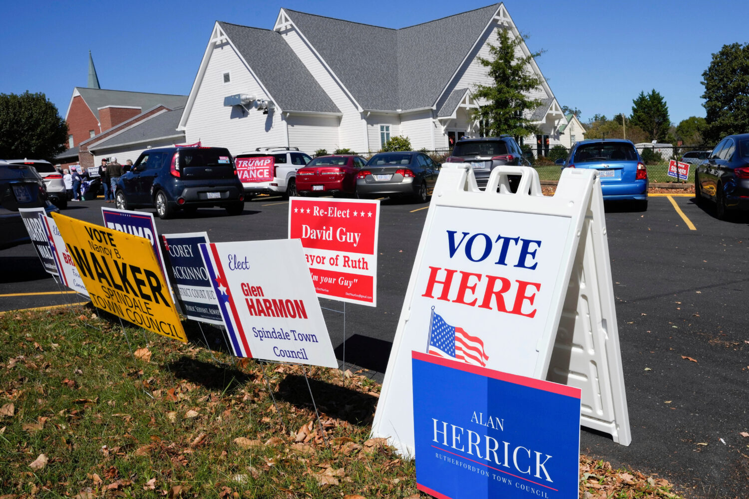 FILE - A Vote Here sign is posted amongst political signs as people arrive to vote at the Rutherfor...