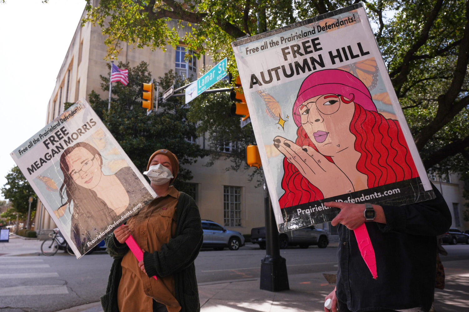 People hold signs across the street from the Eldon B. Mahon U.S. Courthouse during a trial for nine...