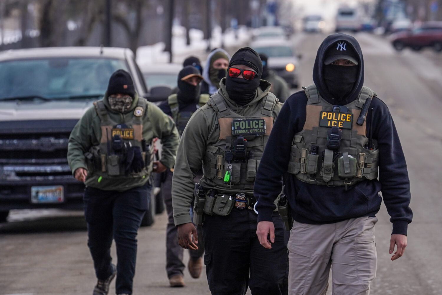 FILE - Federal agents walk down a street while conducting immigration enforcement operations, Thurs...