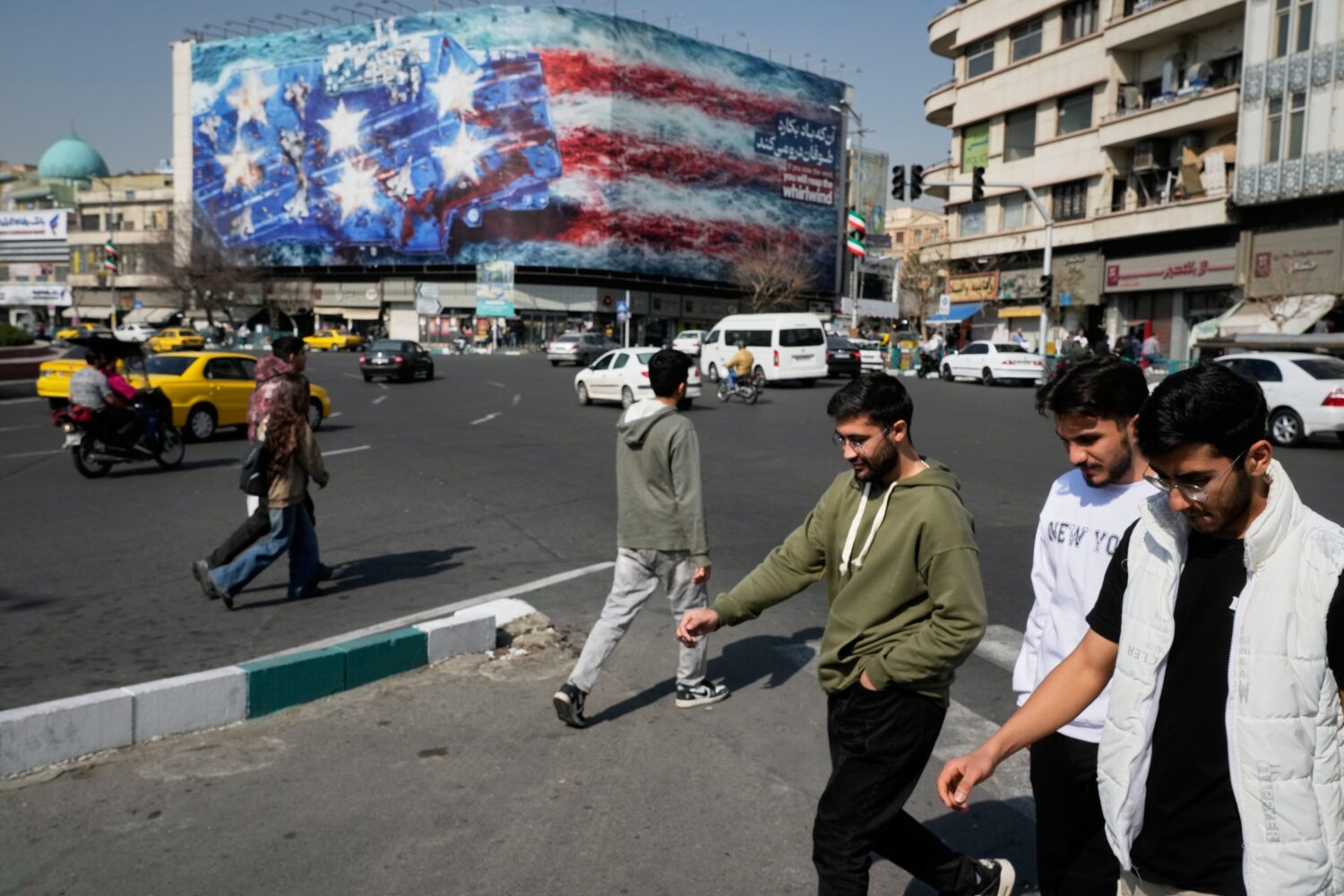 Pedestrians walk past a billboard depicting a U.S. aircraft carrier with damaged fighter jets on it...