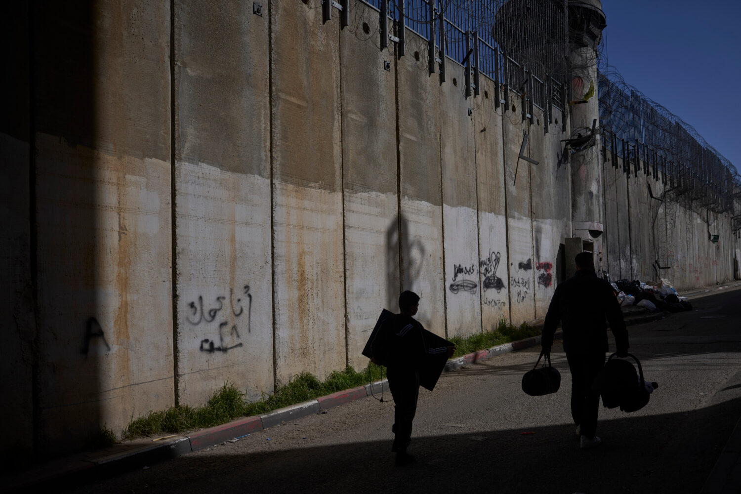 Palestinians walk along the separation barrier between the West Bank and east Jerusalem neighborhoo...