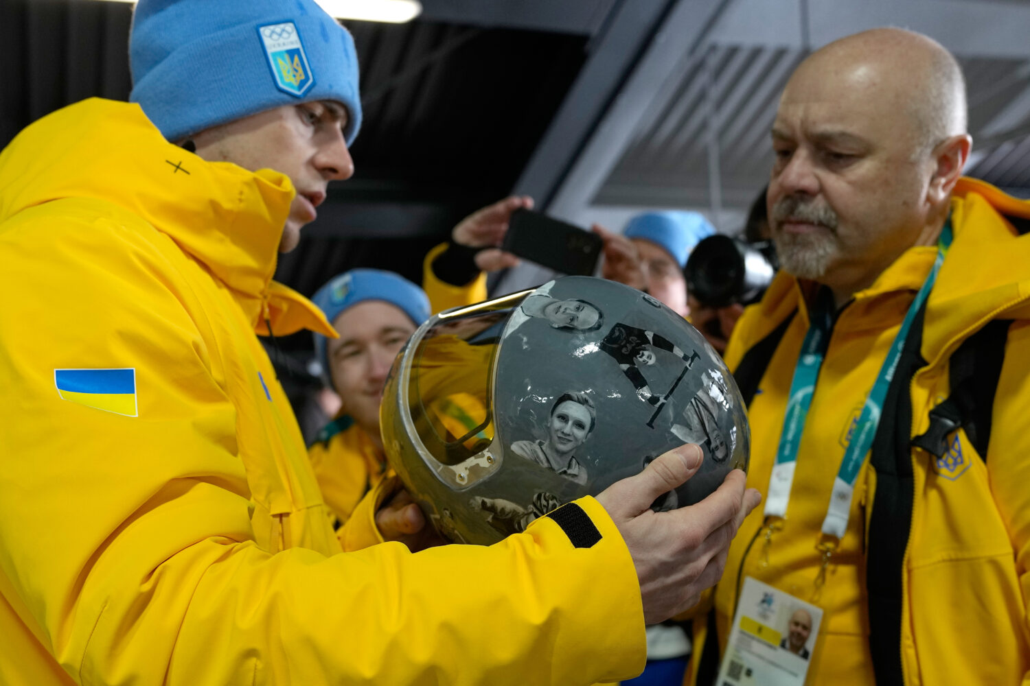 Ukrainian skeleton athlete Vladyslav Heraskevych left, holds his crash helmet at the mixed zone of ...