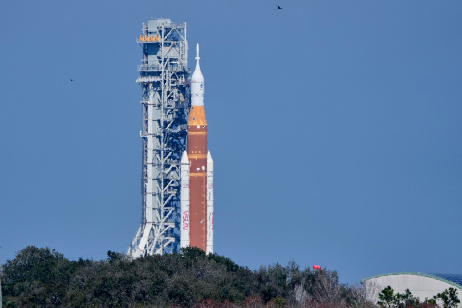 NASA's Artemis II SLS (Space Launch System) moon rocket with the Orion spacecraft slowly rolls back...