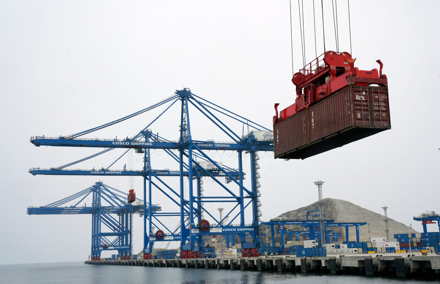 FILE - A container is lifted by a crane backdropped by the construction of the Chinese-funded port,...