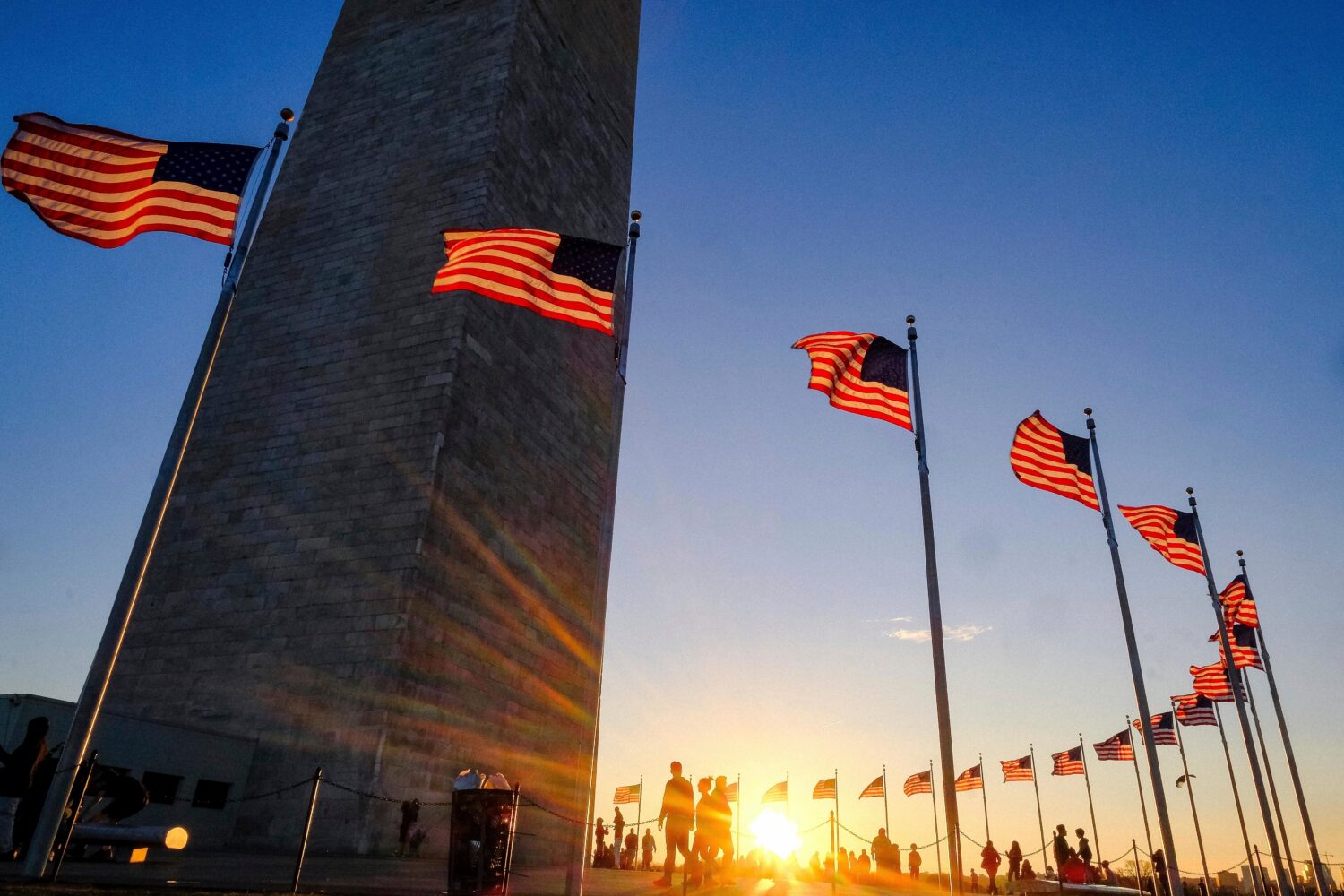 FILE - Tourists walk around the base of the Washington Monument on Presidents Day weekend as the su...