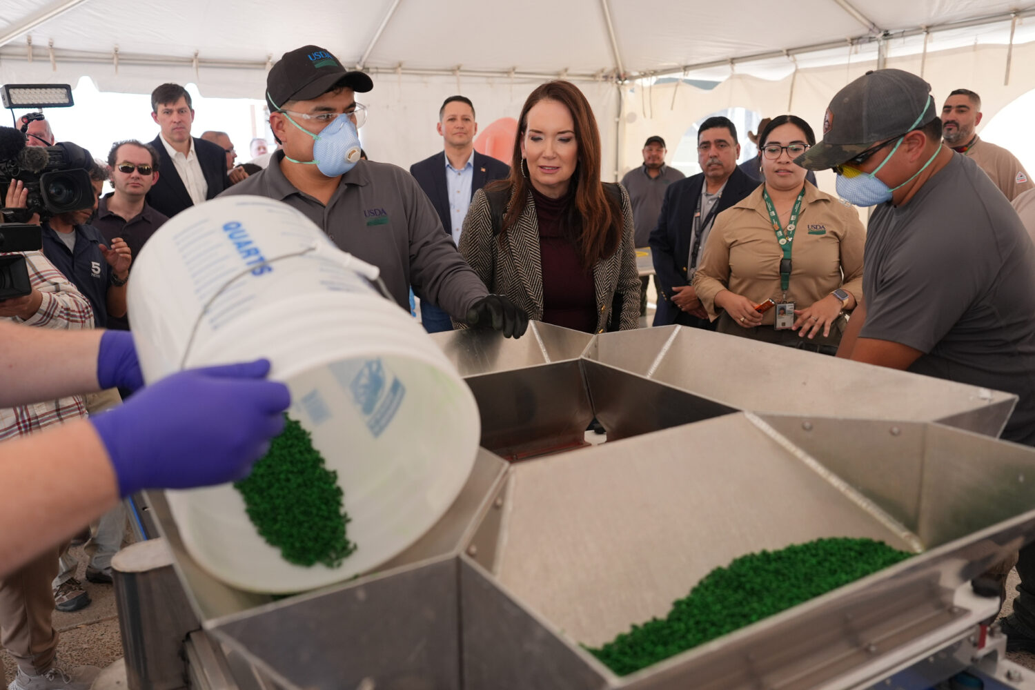 U.S. Secretary of Agriculture Brooke Rollins, center, watches as fly pupae are dyed and separated f...