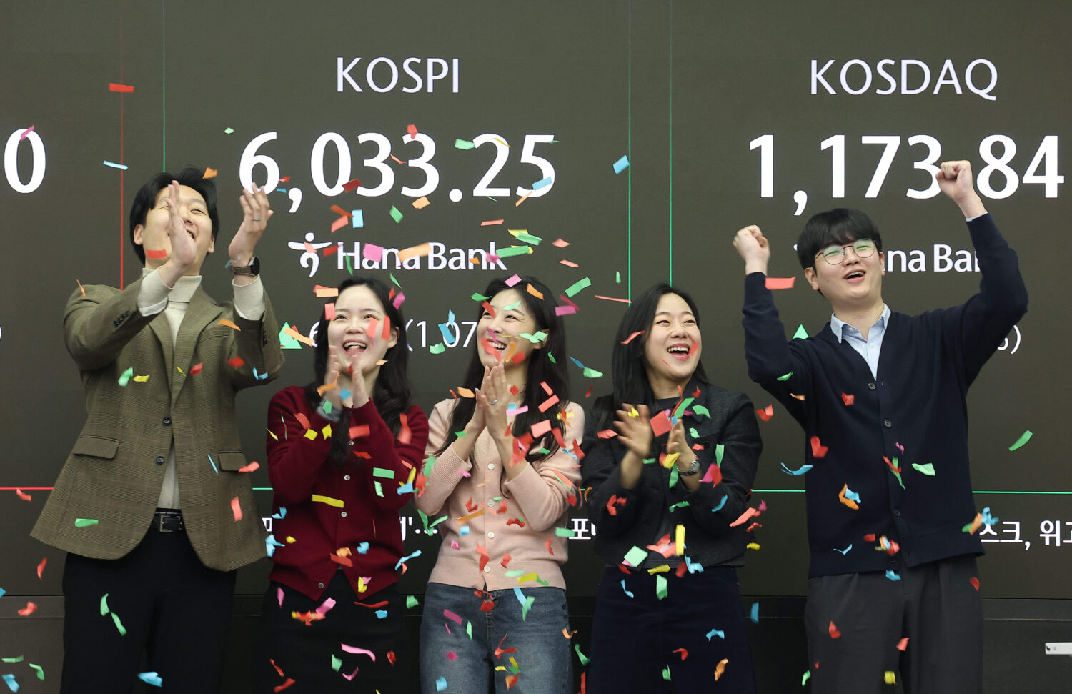 Currency traders celebrate as they work in the office with a screen showing the Korea Composite Sto...