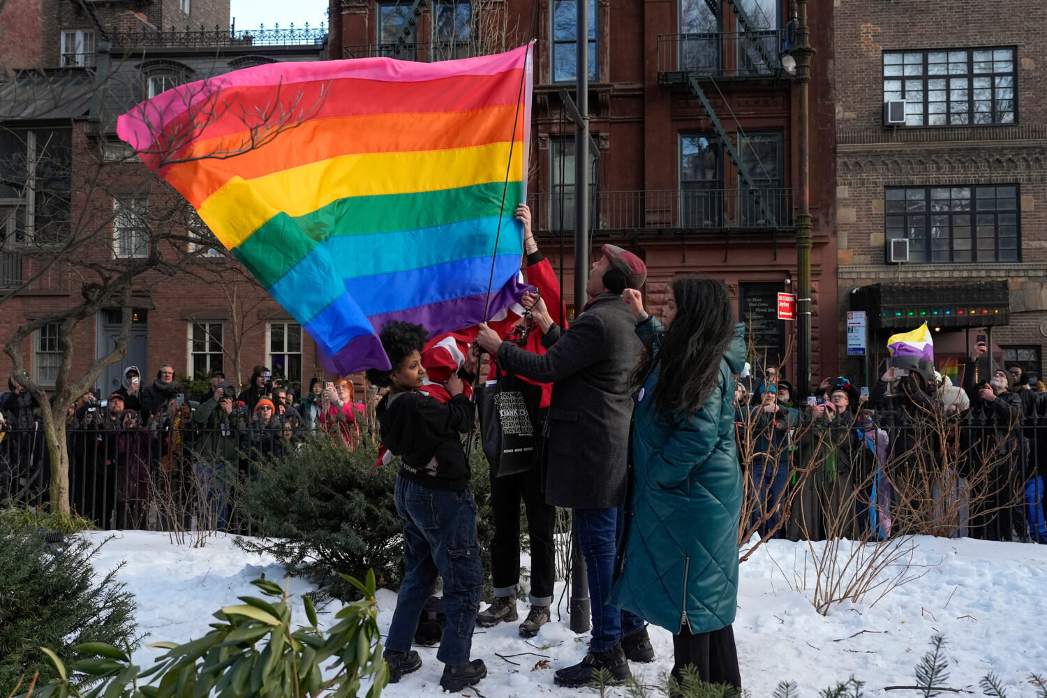 New York politicians and activists raise a rainbow flag on a pole in Christopher Park across the st...
