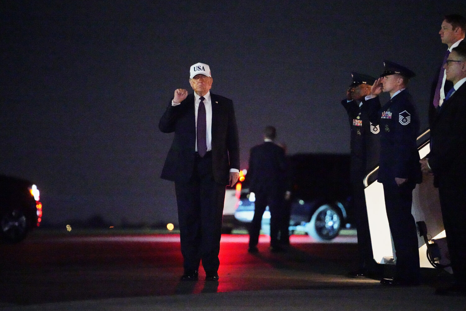 President Donald Trump holds up a fist after disembarking Air Force One at Palm Beach International...