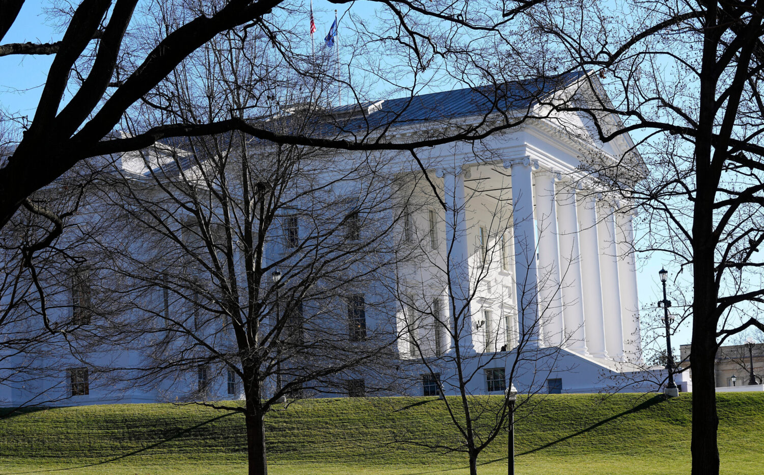 FILE - The state and U.S. flags fly over the Virginia State Capitol as the 2024 session of the Virg...