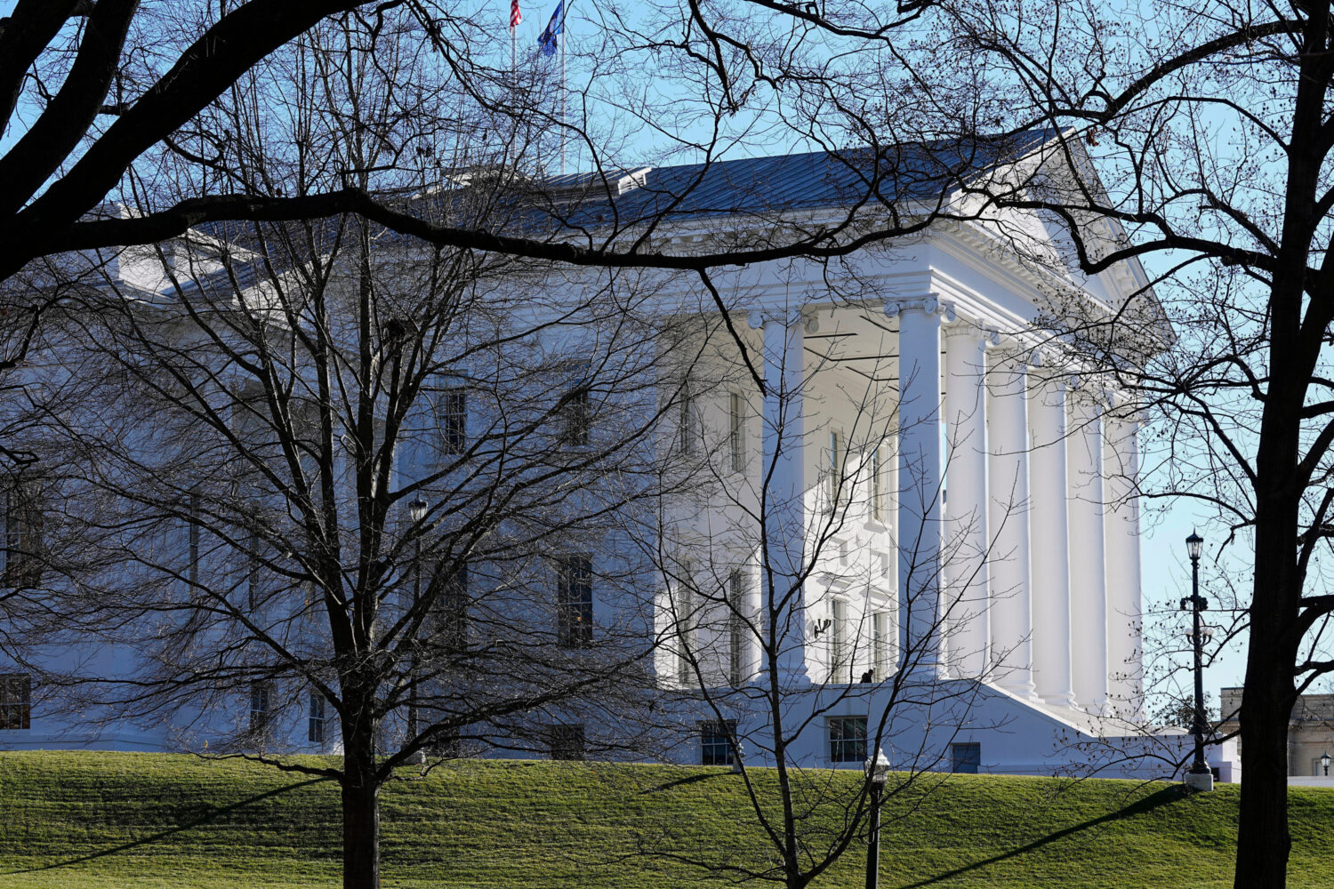 FILE - The state and U.S. flags fly over the Virginia State Capitol at the start of the 2024 sessio...