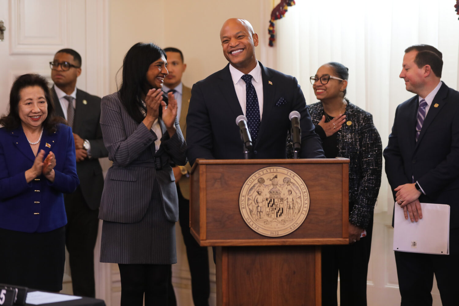 Maryland Gov. Wes Moore, center, smiles before signing legislation that prohibits immigration enfor...