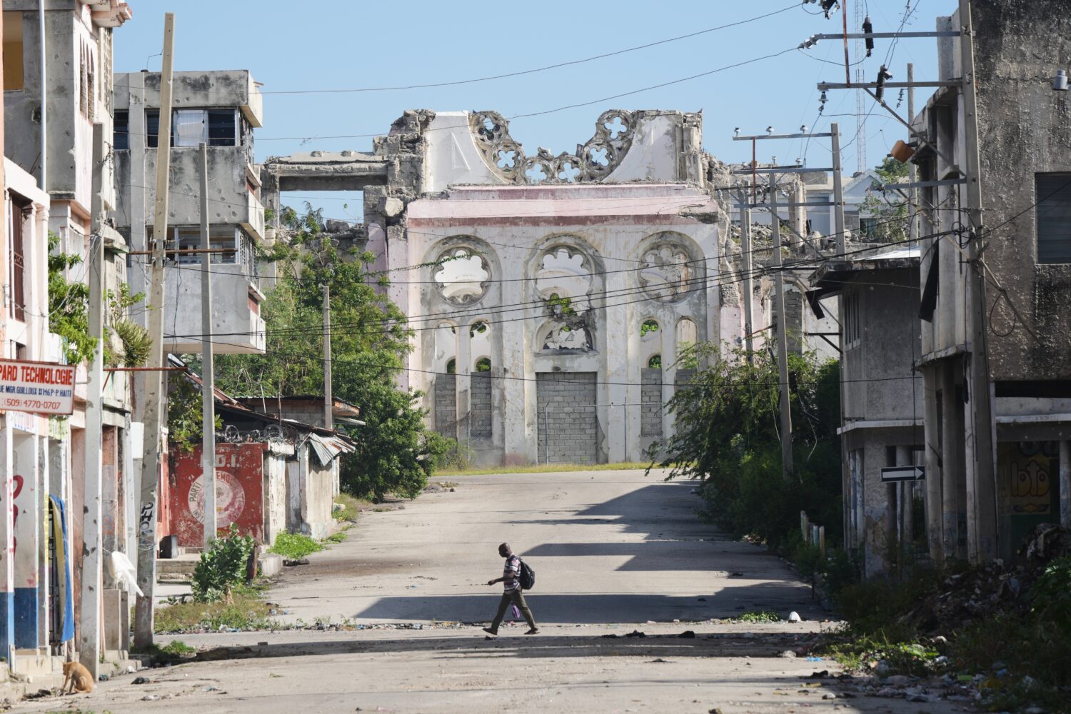 A man walks along a deserted street where a part of the earthquake-destroyed Cathedral stands in do...