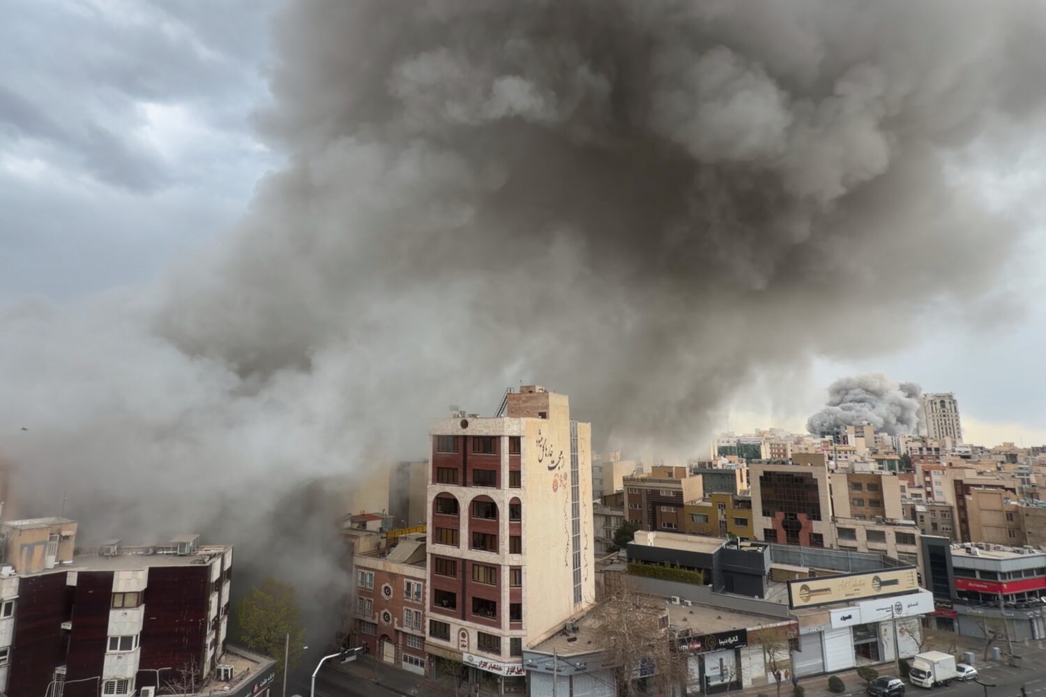Plumes of smoke from two simultaneous strikes rise over Tehran, Iran, Monday, March 2, 2026. (AP Ph...