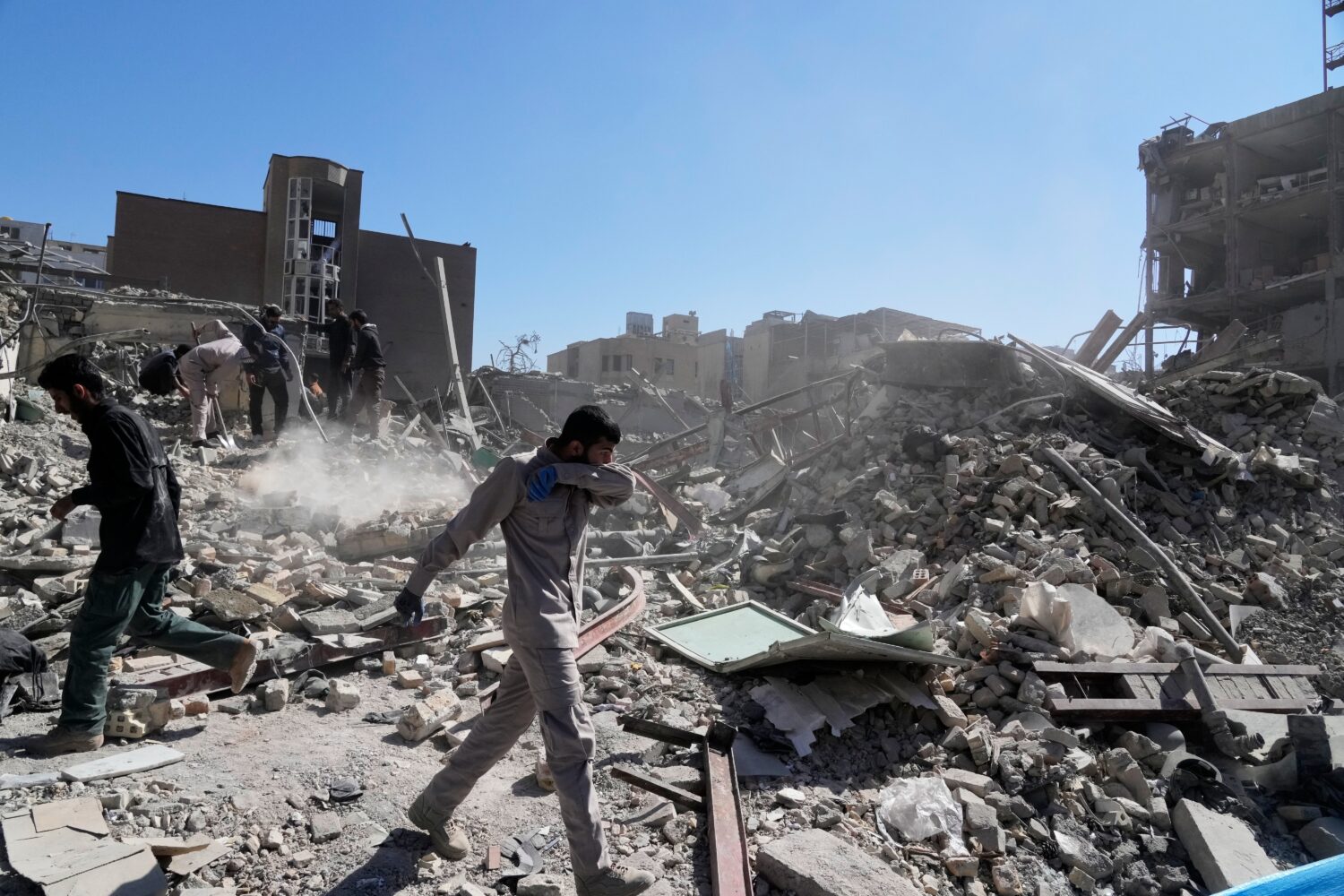 A group of men inspects the ruins of a police station struck Monday amid the U.S.–Israeli militar...