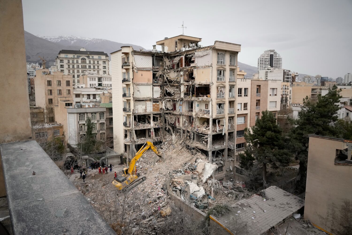 Iranian Red Crescent emergency workers use a bulldozer to clear rubble from a residential building ...
