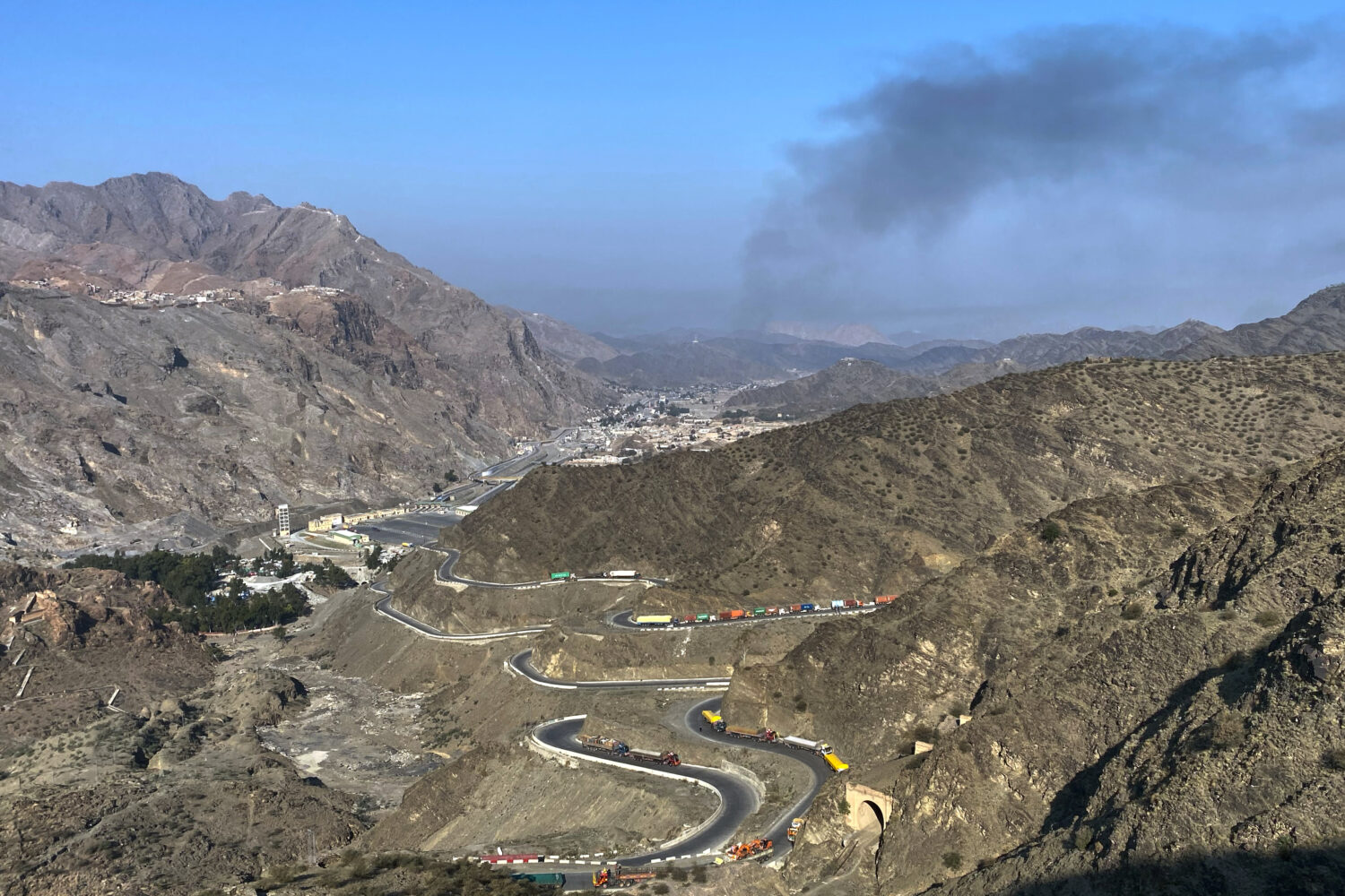 Smoke emits from Afghan side as trucks are parked along roadside following cross-border clashes bet...
