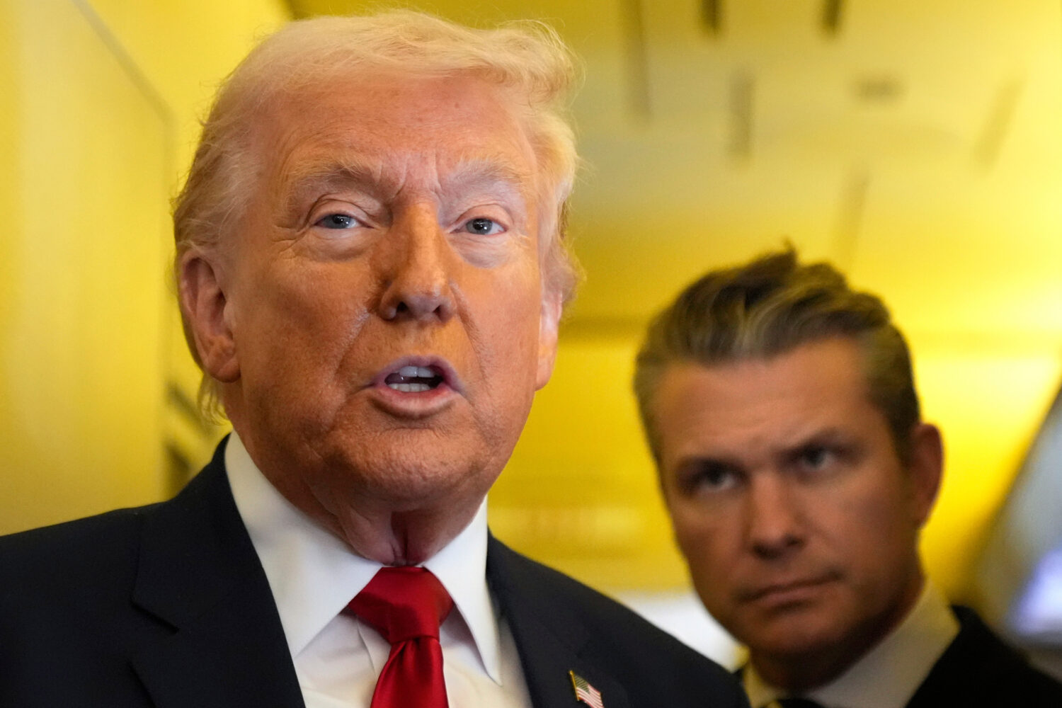 President Donald Trump speaks to reporters as Defense Secretary Pete Hegseth listens while travelin...