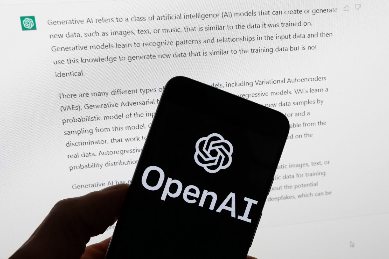 FILE - The OpenAI logo is displayed on a mobile phone in front of a computer screen with output fro...