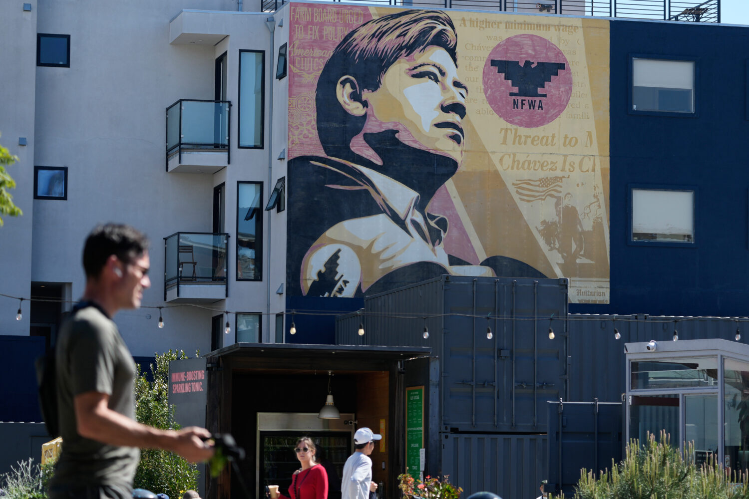 Pedestrians walk below an image of César Chavez on a mural in San Francisco, Wednesday, March 18, ...