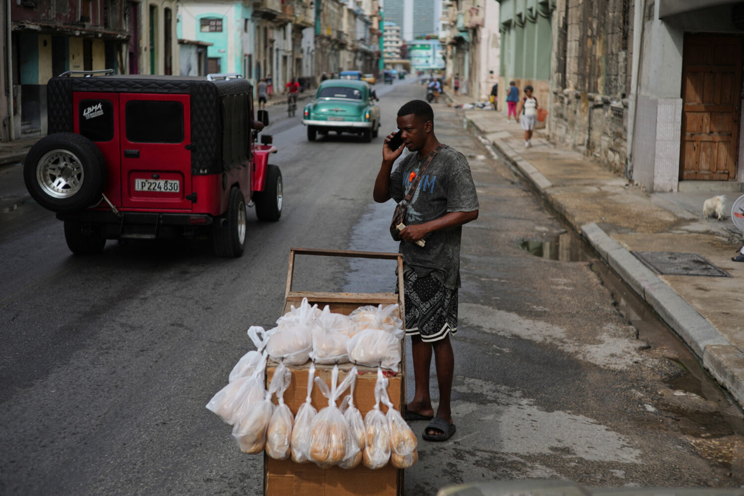 A bread vendor holds a cell phone up to his ear during irregular connectivity due to a blackout in ...