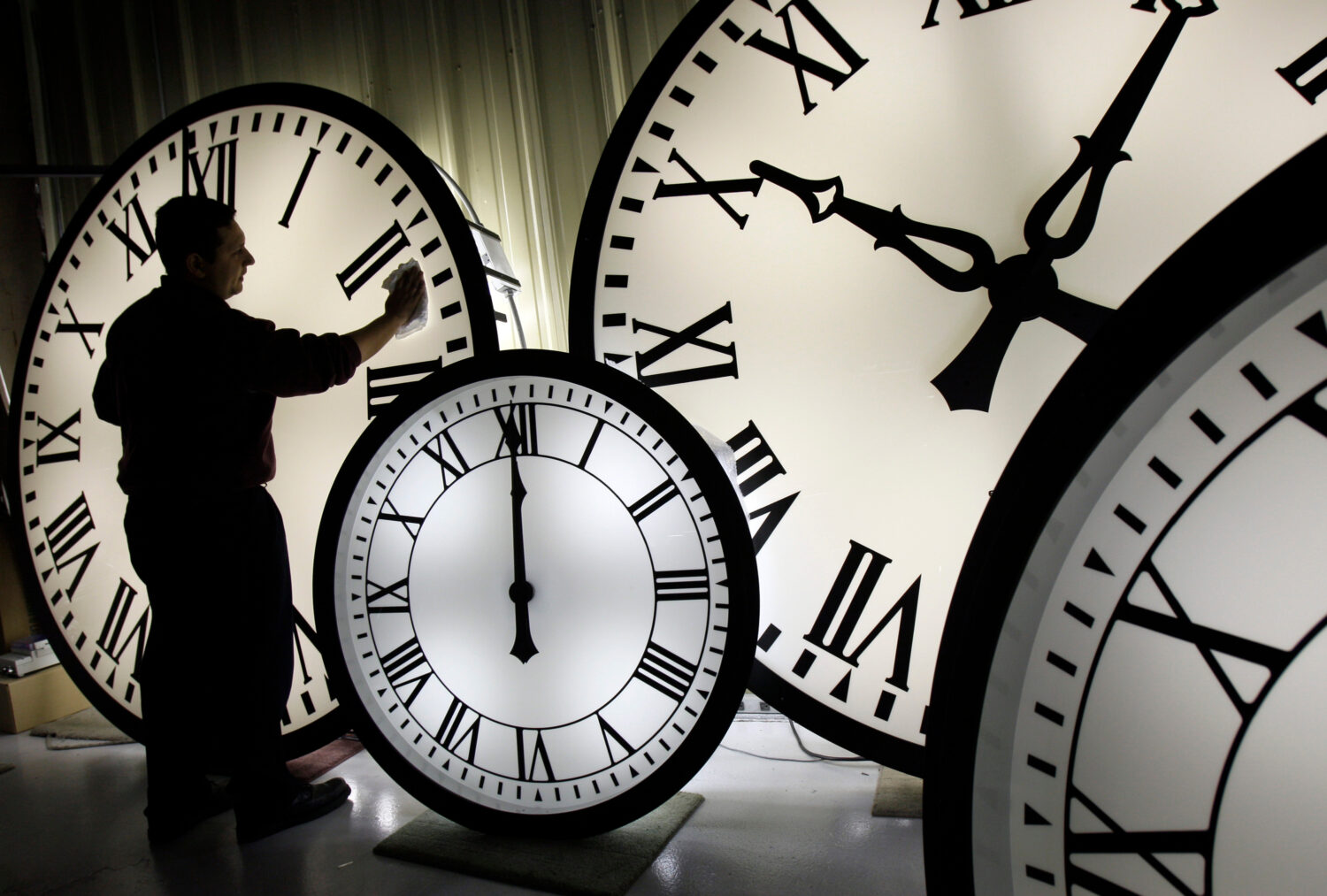 FILE - Electric Time Co. employee Walter Rodriguez cleans the face of an 84-inch Wegman clock at th...