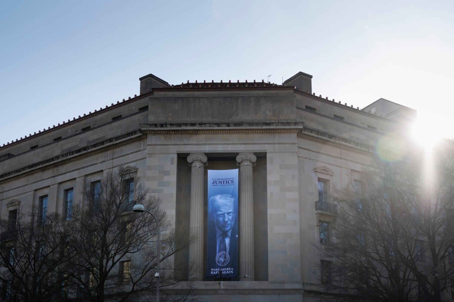 A banner of President Donald Trump hangs outside the U.S. Department of Justice on Saturday, March ...