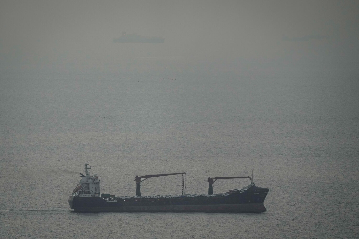 A cargo ship carrying vehicles sails through the Arabian Gulf toward the Strait of Hormuz in the Un...